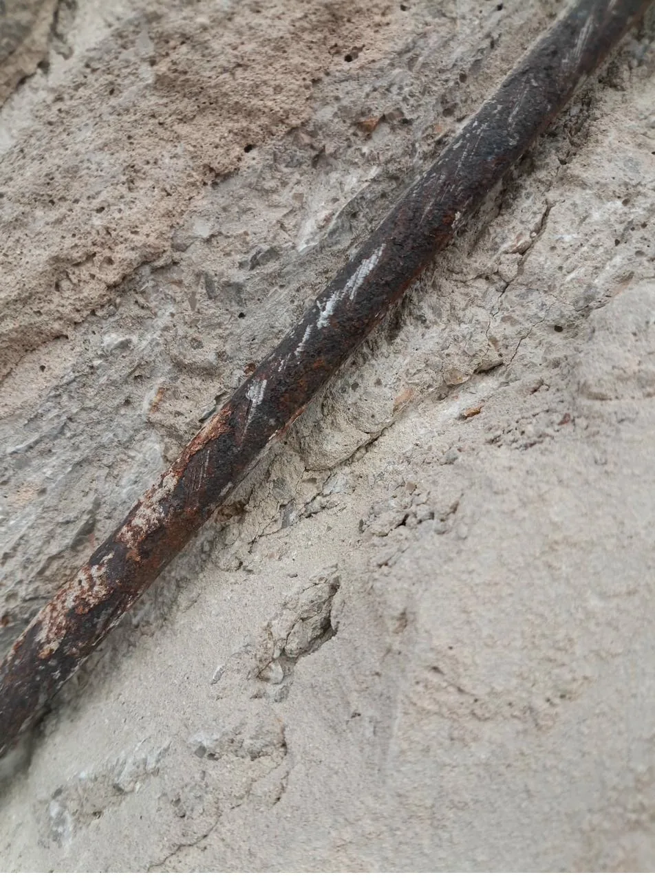 Detalle de armadura oxidada visible en canto de balcón con pérdida de hormigón en fachada de Mallorca