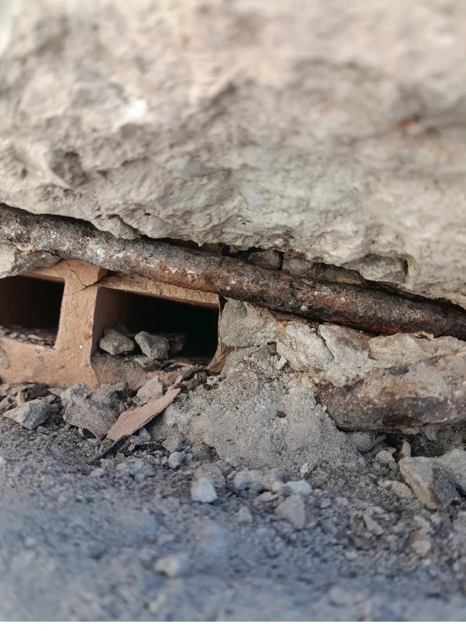 Detalle de armadura oxidada en canto de forjado de un edificio en Mallorca — patología típica que el dossier técnico ITE debe documentar