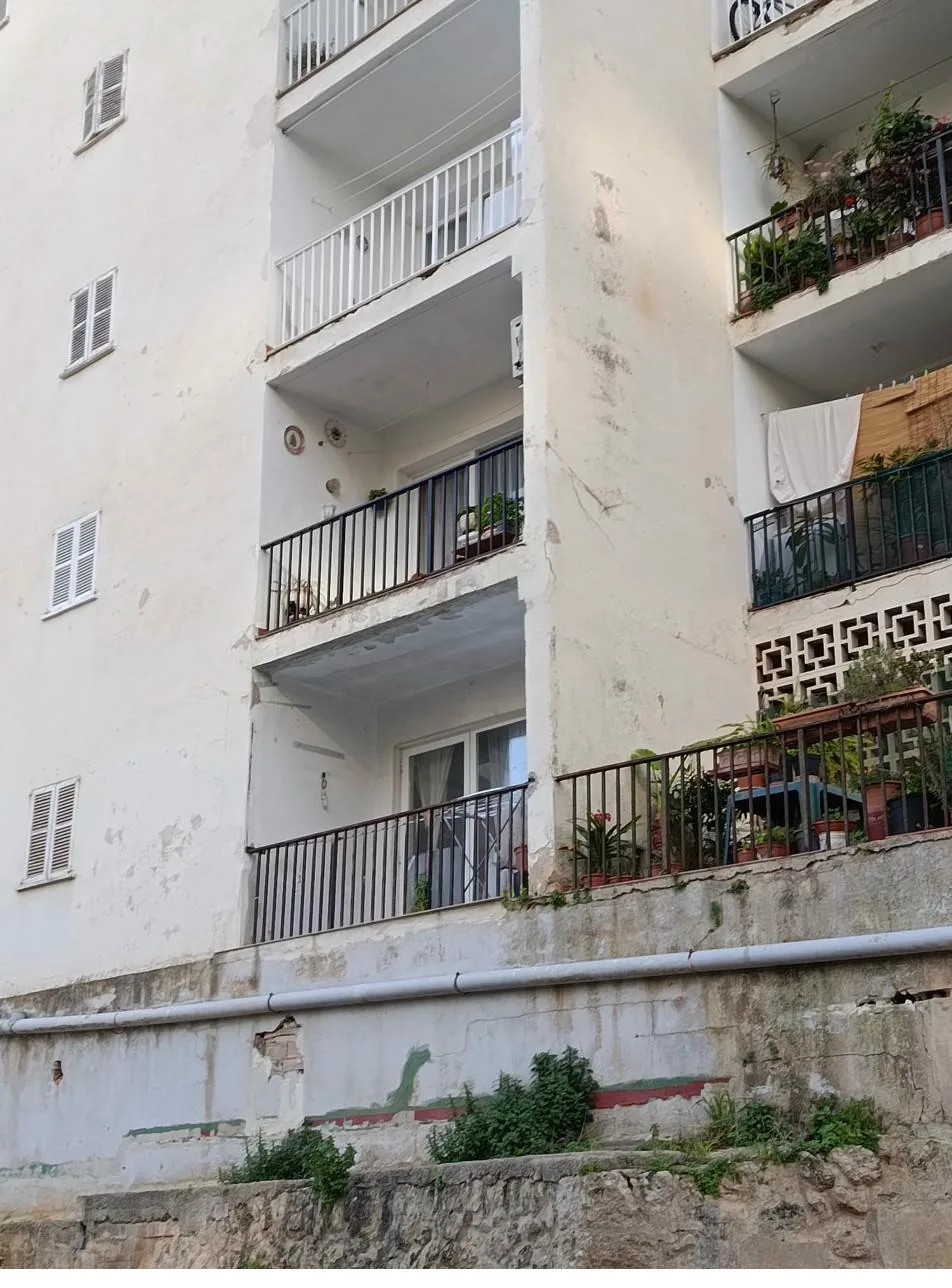 Edificio con fachada y balcones deteriorados en Mallorca, candidato a deficiencias en la ITE por riesgo estructural