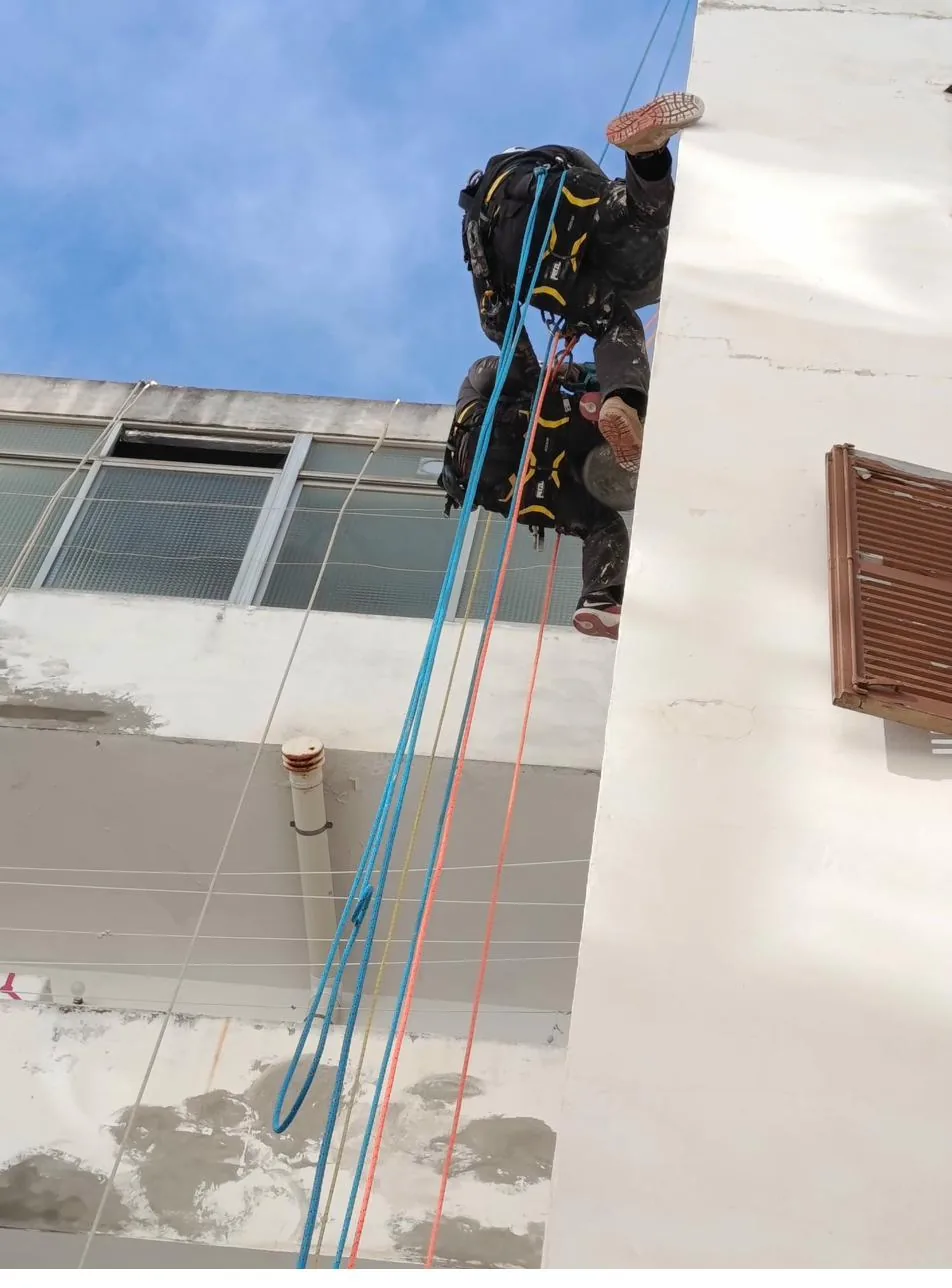 Técnico vertical descolgándose para reparar fachada de comunidad de propietarios